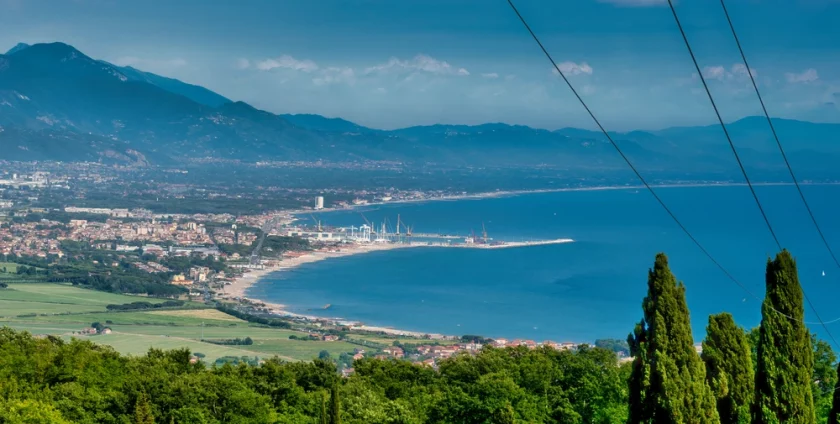 Beautiful view of the marina de Carrara. It is a clear blue sky and bright blue waters with greenery leading towards the marina.