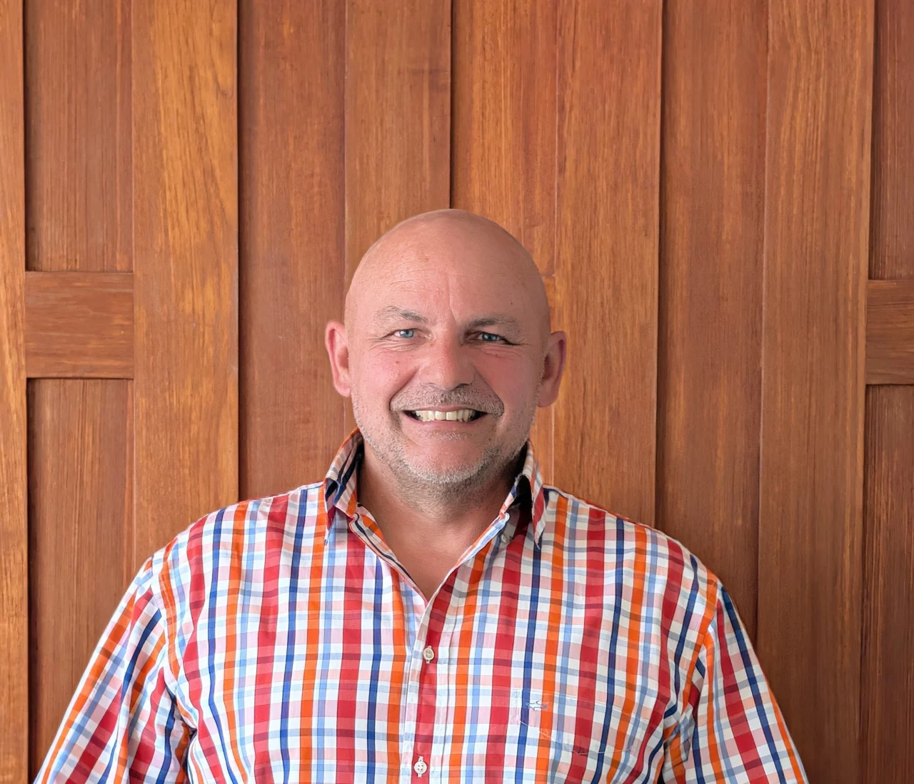 Frank Ravez, the owner of Kreative Decks, stood smiling in front of a wooden door.