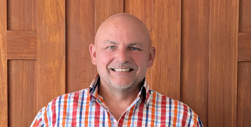 Frank Ravez, the owner of Kreative Decks, stood smiling in front of a wooden door.